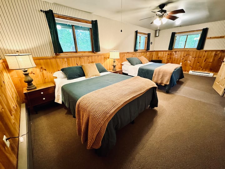 Slaapkamer op lager niveau met twee queensize bedden, vier ramen, grote kast en elektrisch fornuis + plint.