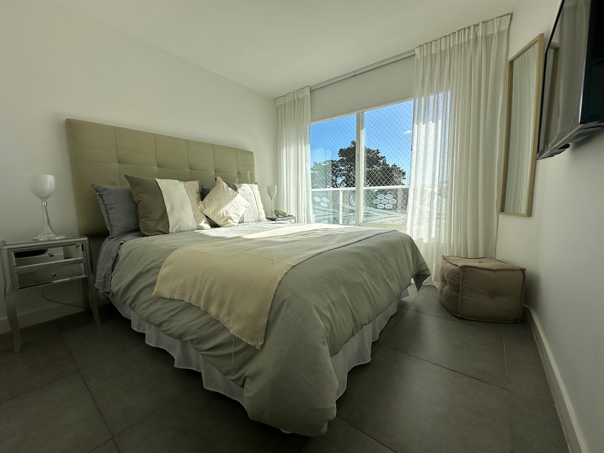 เตียงควีนไซส์พร้อมโต๊ะข้างเตียงและโทรศัพท์เพื่อสื่อสารกับแผนกต้อนรับ