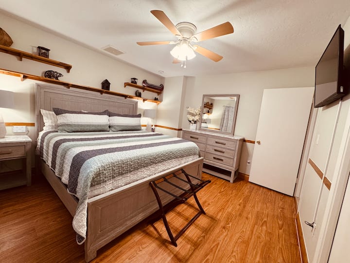 Segundo dormitorio con cama tamaño king, cortinas oscuras y TV inteligente.
Fuente de alimentación ubicada en la pared detrás de cada mesita de noche para una fácil conexión de los cables de carga.