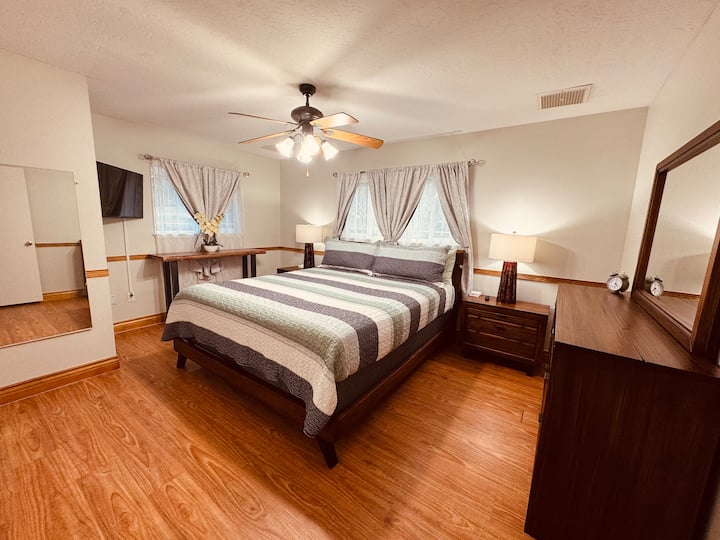Dormitorio principal con cama tamaño king, TV inteligente y cortinas oscuras en la habitación.
Fuente de alimentación ubicada en cada mesita de noche para una fácil conexión de los cables de carga.