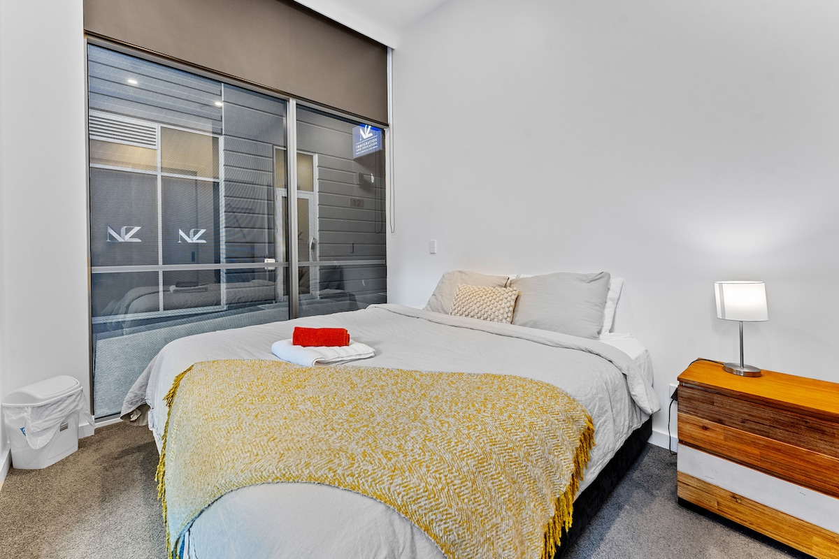 卧室宽敞，配有豪华加大双人床，铺有新洗的床单。 包括舒适的沙发、带台灯的现代床头柜和大玻璃门，提供自然光和宁静的氛围。