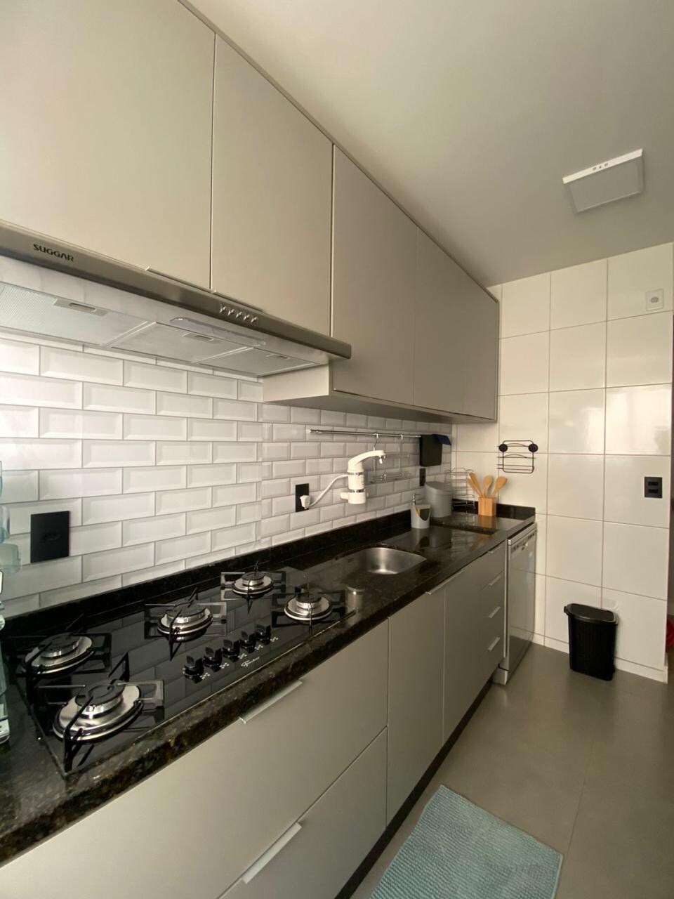 The kitchen features modern cabinetry with sleek gray fronts and a dark granite countertop. Stainless steel appliances, including a gas stove, are complemented by a stylish backsplash made of white subway tiles. A small sink is situated next to a discreet trash bin.