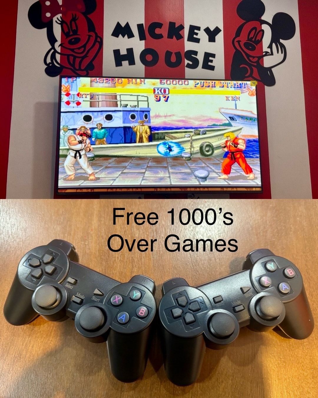 A 55-inch TV displays a vibrant gaming scene against a red and white Mickey Mouse-themed backdrop. Two game controllers are positioned on a wooden surface, highlighting the variety of games available for guests to enjoy.