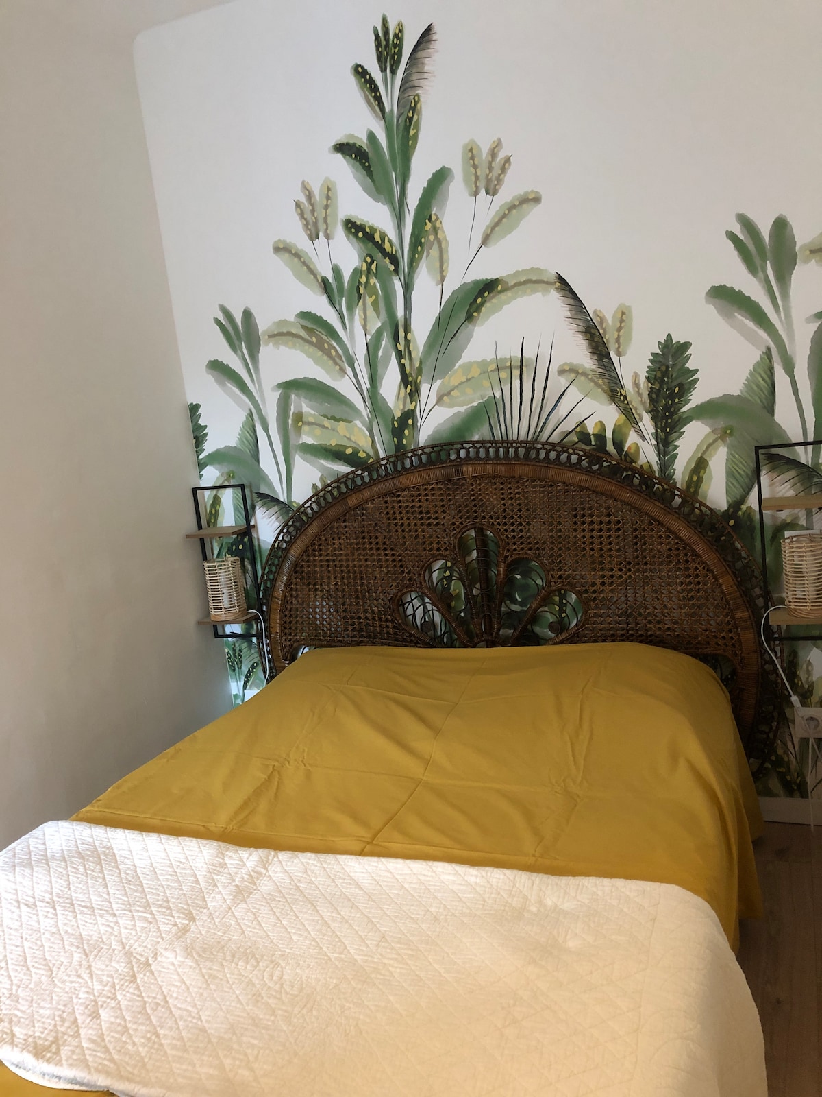 Dhomë gjumi e stilit bohemian e ndarë nga dhoma kryesore nga një perde e trashë, abazhurë pranë krevatit, dollap magazinimi me raft dhe varëse, dysheme prej druri të fortë.