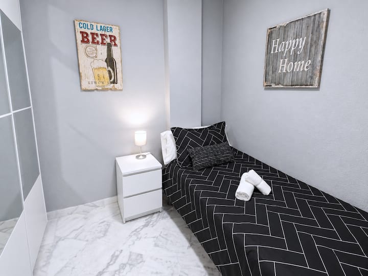 Værelse med en 0,90 x 1,90 m (3 x 6 fod) enkeltseng, et stort skab med spejle og bøjler, et natbord med en lampe og en loftventilator med fjernbetjening og dæmpbart lys.