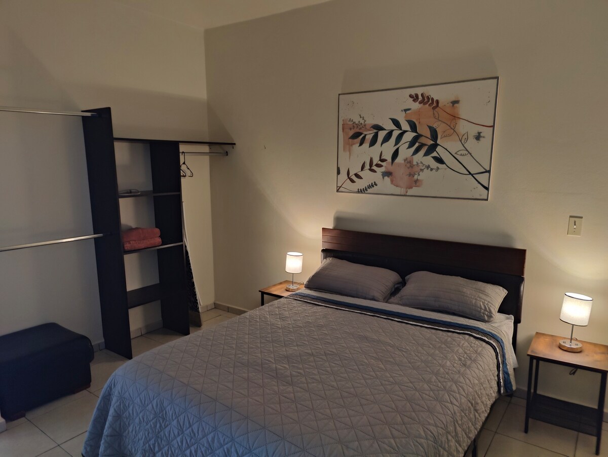 Recámara con cama queen, aire acondicionado, clóset y tv.