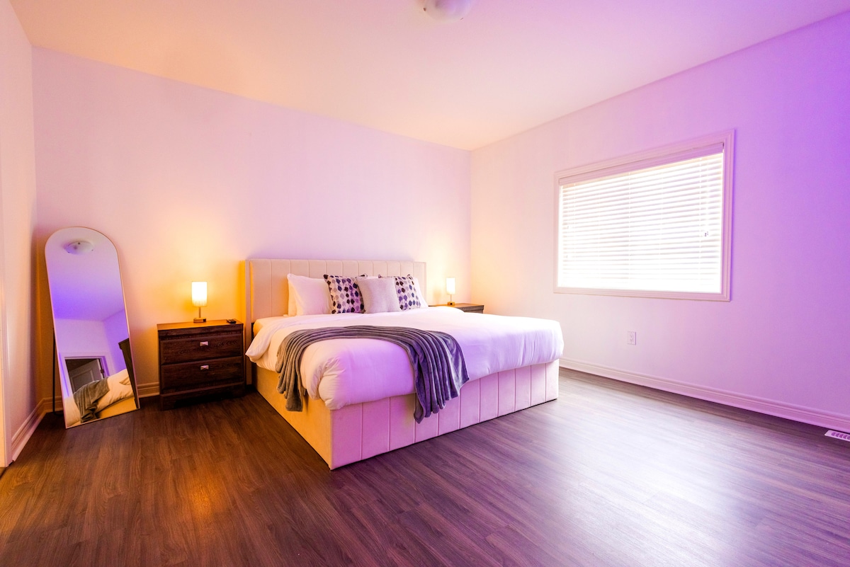 Strehë e gjerë me një krevat dopio "king" të butë, ndriçim të ngrohtë dhe stil modern elegant.