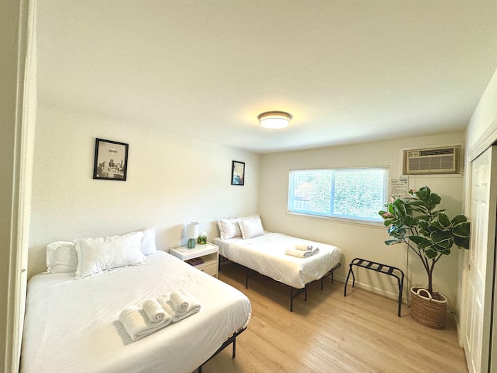 这间卧室配有两张全尺寸床。 床之间有一个白色的床头柜。 非常适合接待多位房客。