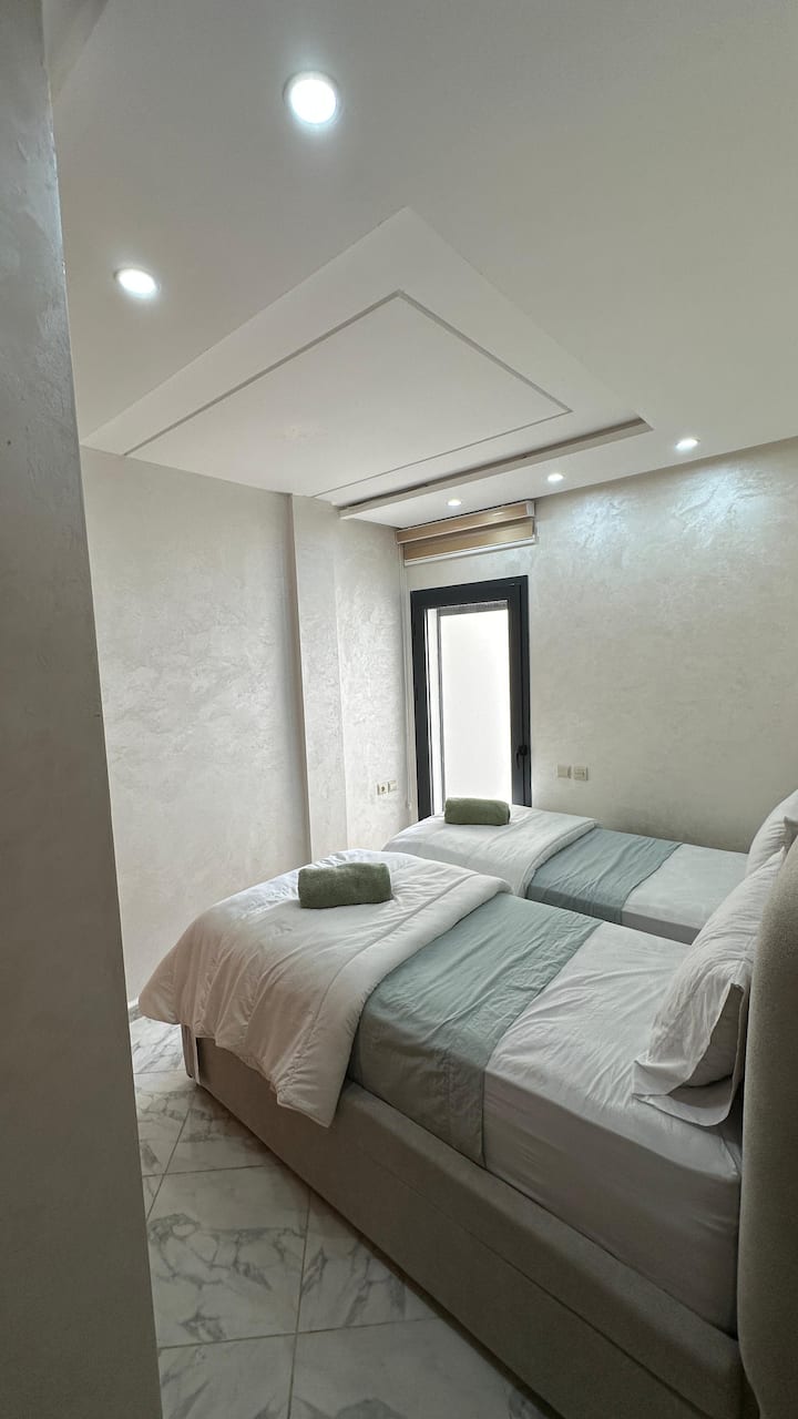 חדר שינה נעים עם שתי מיטות, ארון מרווח ומתלים, ומרפסת פרטית, המספקים מרחב אידיאלי למנוחה ורגיעה באווירה נקייה ואלגנטית לאורחים המחפשים נוחות ויוקרה.
