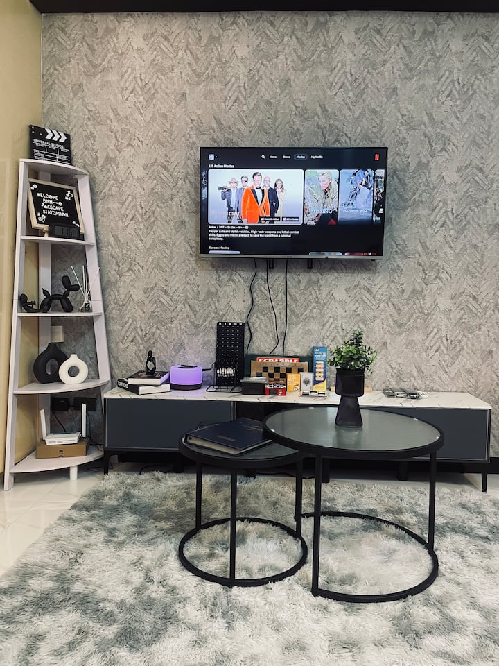 ادخل إلى منطقة المعيشة الأنيقة بالأبيض والأسود، حيث يلتقي التصميم الحديث بالترفيه. استمتع بتلفزيون ذكي مع نيتفليكس مجاني، ومجموعة متنوعة من ألعاب الطاولة، ونظام كاريوكي بلاتيني، وهو مثالي للأمسيات المليئة بالمرح.