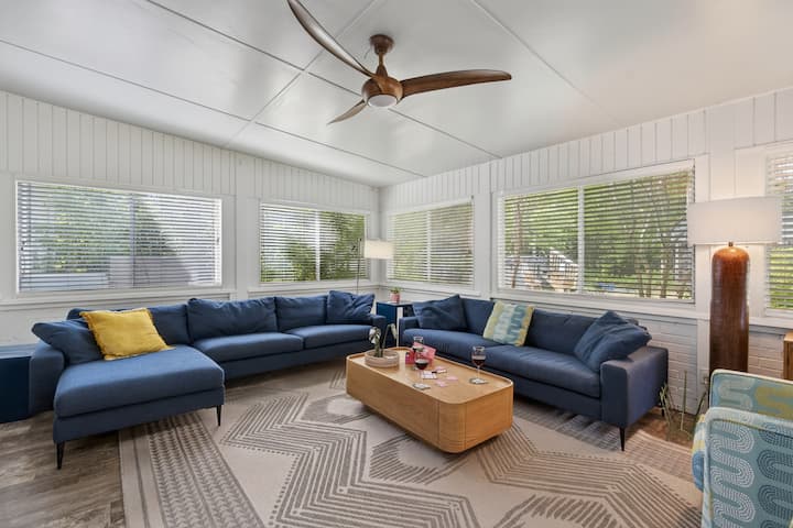 Bright and welcoming, this spacious living room features oversized sofas, stylish seating, large sun-filled windows, a flat-screen TV, and modern wood accents—creating the perfect space to relax, gather, and unwind with family and friends.
