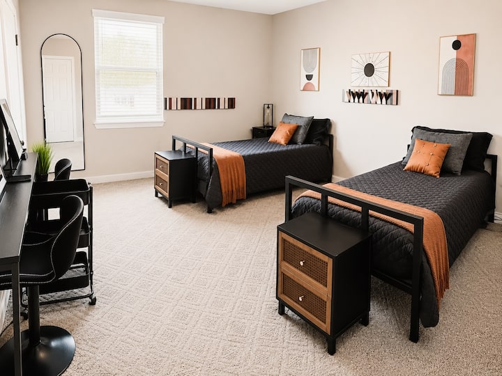 The second bedroom features two twin beds plus a twin trundle bed, providing sleeping space for up to three guests. The room also includes two lighted vanity mirrors with chairs, a full-length mirror, and a closet.