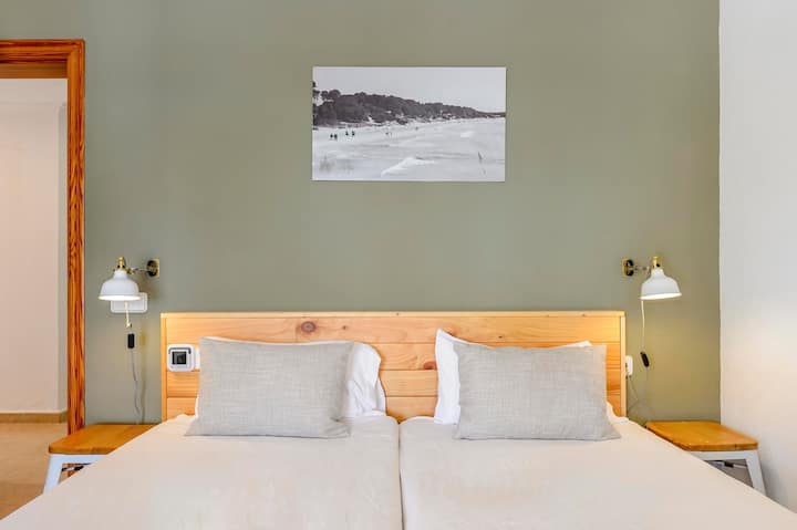 Prostrana dvokrevetna soba uređena u umirujućim tonovima s udobnom posteljinom u hotelskom stilu.