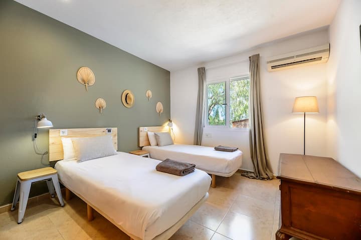 Twin bedroom with green feature wall and woven wall decor, Villa Suki, Ibiza.