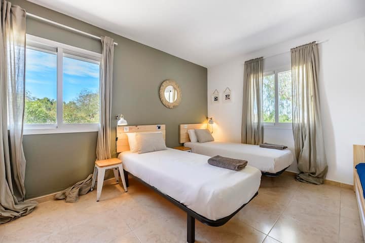 Bright twin bedroom with a green feature wall and countryside views, Villa Suki, Ibiza.
