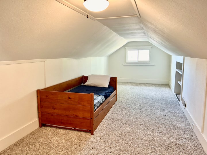The attic space features a twin trundle bed with an additional pullout twin mattress, and spare blankets on the shelf. A Pack-and-Play is stored in the closet, and a portable AC/heater/dehumidifier keeps the space comfortable year-round.