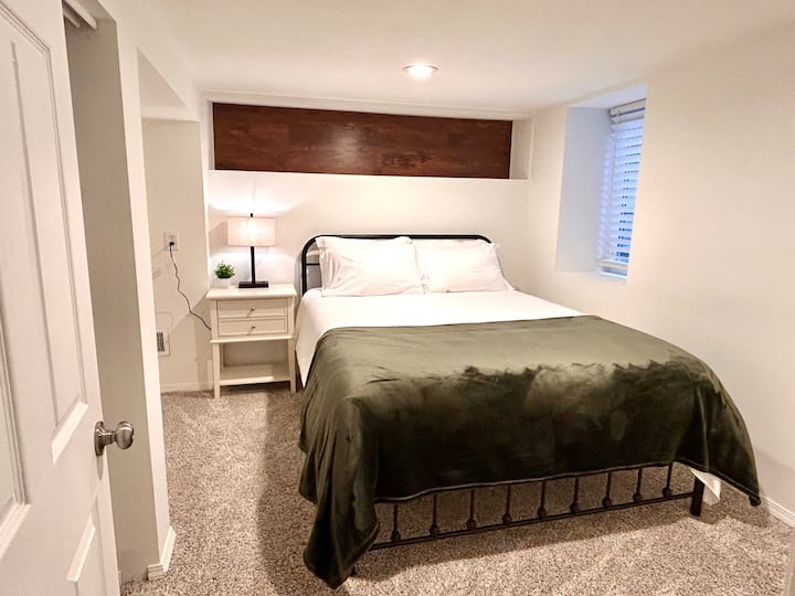 Lower-level bedroom with queen bed, nightstand, and closet space — a comfortable retreat for guests seeking privacy and relaxation during their Spokane stay.