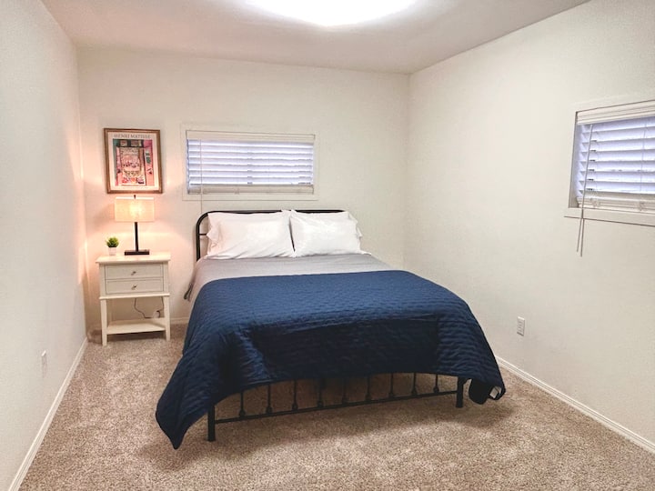 The master bedroom on the main floor offers a comfortable queen bed, nightstand with lamp, dresser and closet for storage, and a mirror for getting ready — a peaceful space to unwind and recharge.