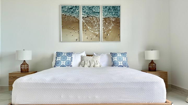 King Bed Bedroom Ocean View on 2nd floor with private balcony. Your private master retreat ✨ — a king bed sanctuary with soaring 11-ft ceilings and sweeping ocean views. A plush king bed, coastal artwork, and warm accents for a calm island retreat.