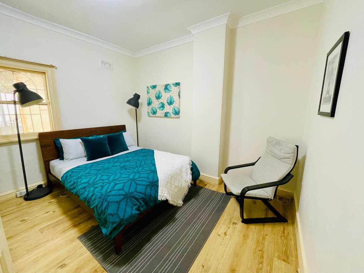 Relájate en nuestro acogedor dormitorio, con una lujosa cama tamaño queen para una noche de sueño reparador y una cómoda tumbona para relajarse. La habitación también incluye un práctico riel colgante para tu ropa, lo que garantiza que todo se mantenga organizado y al alcance de la mano.