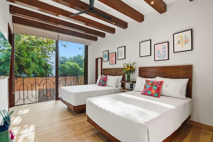 Camas dobles de tamaño completo en un espacio lúdico, luminoso y espacioso con vistas a la selva y a la piscina. Baño privado con ventanas