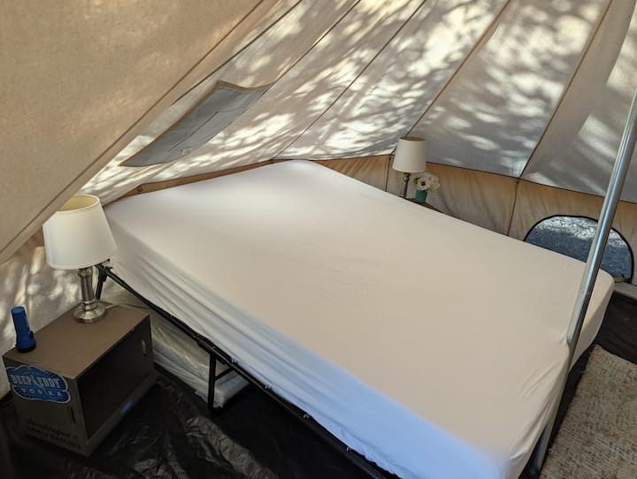 BYOBedding: Descansa tranquilo en una acogedora cama tamaño queen, mantenida fresca con un enfriador de pantano en días más cálidos. Hay una lámpara suave y un práctico enchufe cerca para el cargador de tu teléfono, lo que garantiza una estancia tranquila y cómoda. No dudes en traer sacos de dormir/cunas adicionales. 