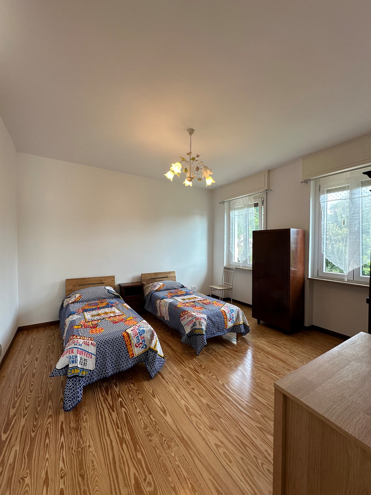 Një dhomë gjumi me dy krevate tek dhe një dritare dopio me pamje nga liqeni Orta. 