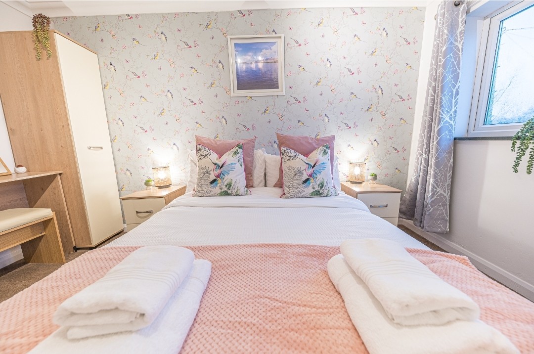 Ontspan in stijl met zacht beddengoed, decoratieve frames en warme verlichting voor een perfect toevluchtsoord.