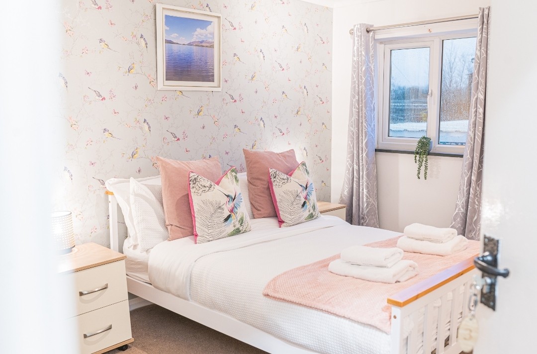 Een serene slaapkamer met zacht beddengoed, een warme lamp en persoonlijke accenten in ingelijste decoratie.