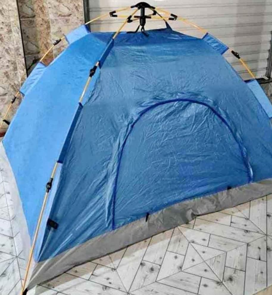 A blue tent is displayed in the image, featuring a streamlined design with a prominent entrance. The tent is set on a patterned wooden floor, showcasing its spacious interior and sturdy poles. The fabric appears weather-resistant, suitable for various placement options.