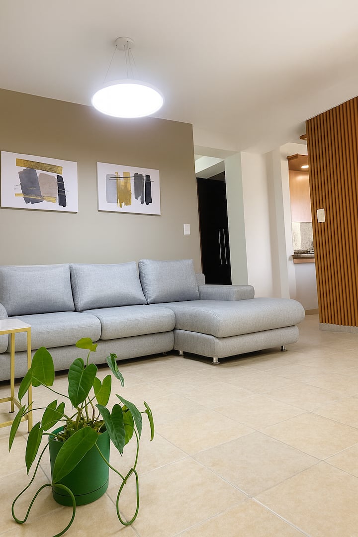 منطقة غرفة المعيشة حيث يتم الجمع بين التفاصيل الحديثة والخشب والنباتات الطبيعية، مما يخلق جوًا دافئًا ومريحًا. مكان مثالي للراحة أو المشاركة أو الاستمتاع بوقت هادئ أثناء إقامتك.