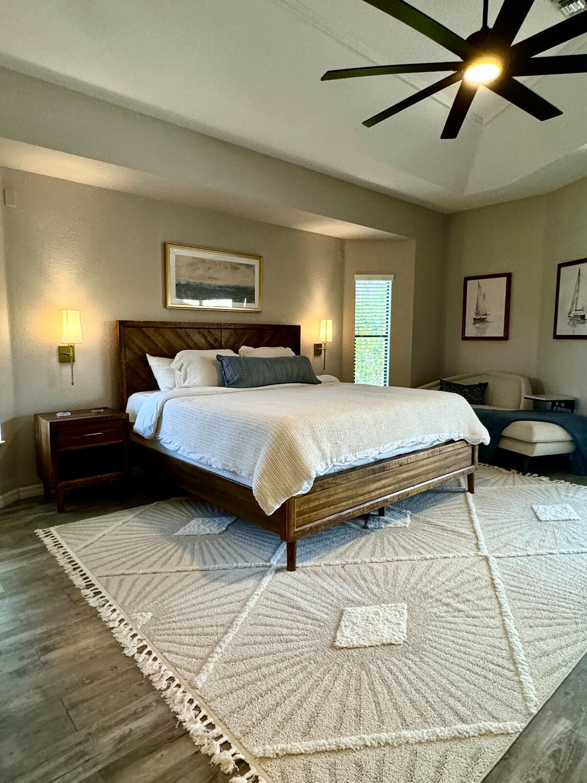 חדר השינה הראשי כולל מיטה מפוארת בגודל קינג סייז, פמוטים אלגנטיים וטרקלין כיסאות אופנתי - המקלט המושלם למנוחה ורוגע!