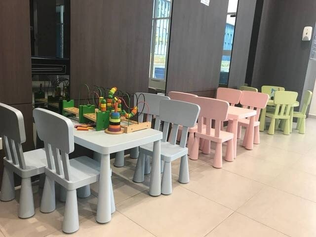 A designated children's area features colorful furniture, including several small tables and chairs in pastel colors. Engaging toys are visible on the tables, along with a play activity set that encourages creativity and play. The floor is covered with smooth tiles, enhancing accessibility.