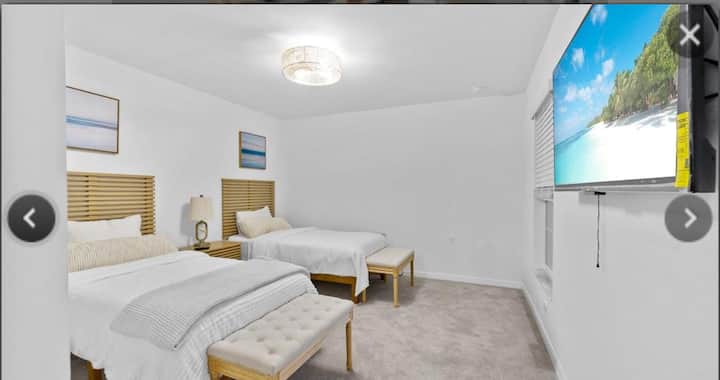 Chumba cha kulala cha wageni kilicho na vitanda viwili maridadi na televisheni ya skrini tambarare iliyo tayari kwa ajili ya kutazama mtandaoni.  Feni ya dari/taa ya dari imeunganishwa katika moja ili kupoza na kuangaza chumba.