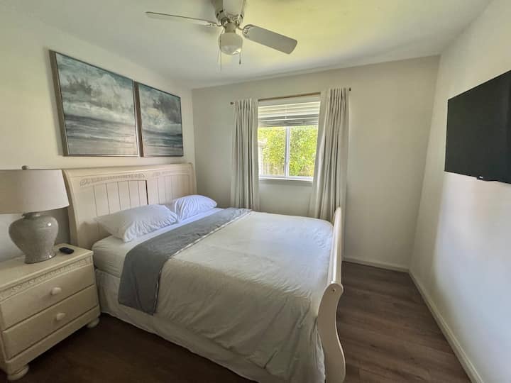 Habitación acogedora con una cama tamaño queen, televisor de 44 pulgadas, vestidor, espacio en el armario, ventilador y cortinas opacas para una estancia cómoda y tranquila.