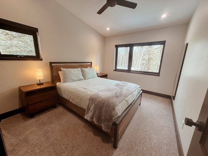 Charmante chambre d'hôtes avec un lit queen et de la lumière naturelle qui s'écoule des fenêtres environnantes.
