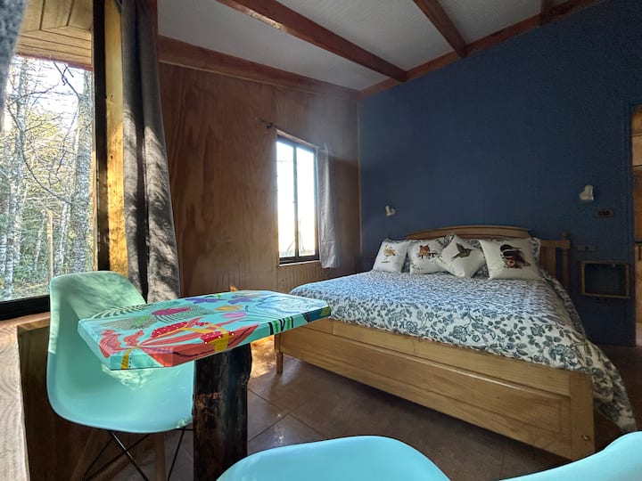 Udoban bračni krevet s pogledom na autohtonu šumu Villarrica. Bow window with table and seating for breakfast, or sitting down to read a book by the milenary trees.
