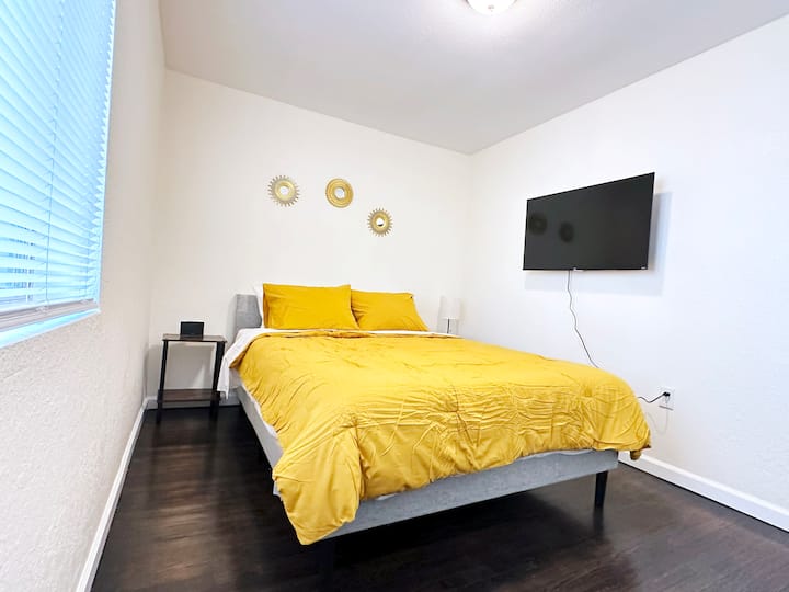 Spálňa s manželskou posteľou, budíkom, dvoma nočnými stolíkmi, lampou a inteligentnou televíziou