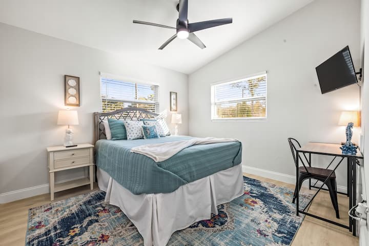 Bedroom 2 | Second bedroom with Queen bed, dedicated workspace, smart TV, closet storage with hangers, hamper and luggage racks, vaulted ceiling and ceiling fan.