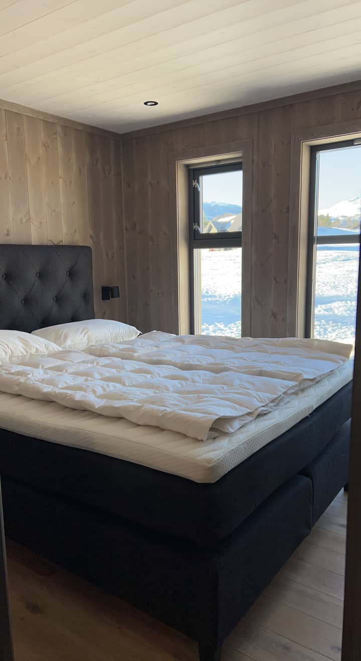 Lit 160x180 Signature Collection avec édredons et oreillers en duvet. Tables de chevet et lampes murales en plus d'un endroit à intensité variable sur les plafonds 