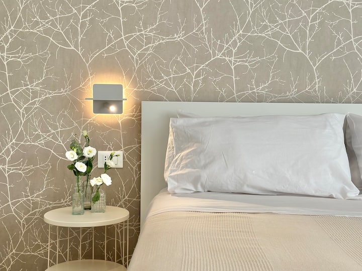 Ampia e luminosa camera da letto matrimoniale, con comodini, armadio con poggia valigie, scrittoio con pouf e specchio da tavolo, specchio grande a muro, Smart tv 32''; accesso a bagno privato.
