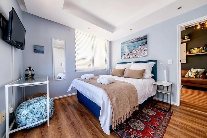 Chambre principale avec lit double, éclairage doux et télévision en streaming.