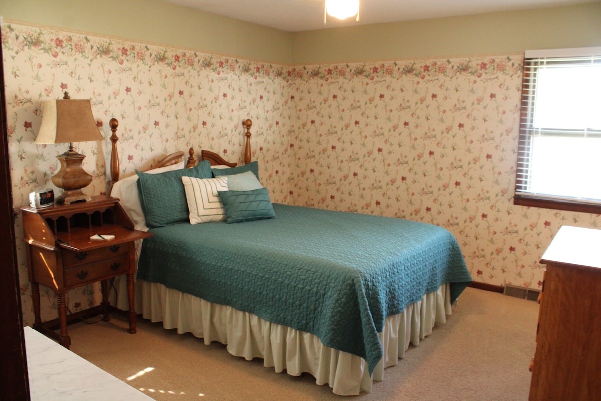 Queensize, achterslaapkamer. Uitzicht op de achtertuin en boom/meer. En-suite complete badkamer. 