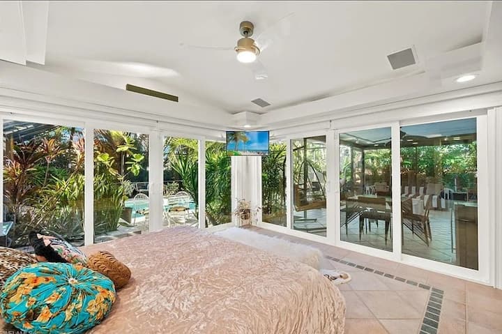 Luxurious Naples Retreat: Spacious master bedroom with sliding doors to the private pool and lush tropical gardens.
Naples Getaway: Enjoy the ultimate comfort in this elegant bedroom with a king-size bed and stunning outdoor views.