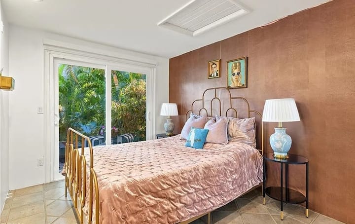 Large sliding glass doors allow natural light to flood the space while offering a serene view of lush greenery outside. This bedroom is ideal for couples or solo travelers looking for luxury Airbnbs in Naples, FL or romantic holiday homes.