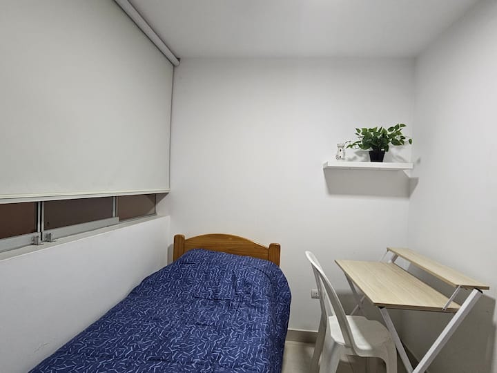 Cama de una plaza,  perchero,  escritorio y  silla.
