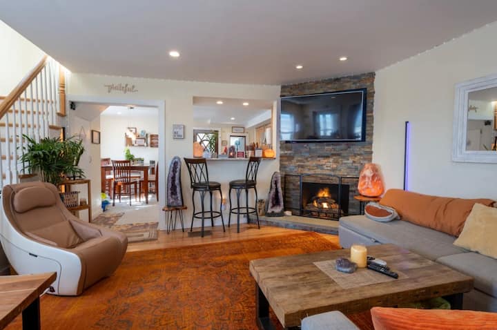 Отворен концептуален дневен простор со поглед кон океанот, двоен футон на извлекување, кауч на извлекување, паметен телевизор, внатрешен камин на плин, простор за барчиња, стол за масажа, масички за кафе, игри на табла, кристали и удобен декор.