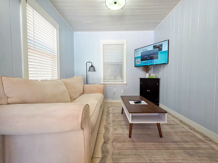A sala de estar possui um sofá com uma cama dobrável, um tapete de área lavável na máquina, mesas laterais com luzes e estação de carregamento, uma grande TV de streaming e uma mesa de centro retrátil que você pode usar como espaço de trabalho ou para refeições. Novas fotos melhores em breve.