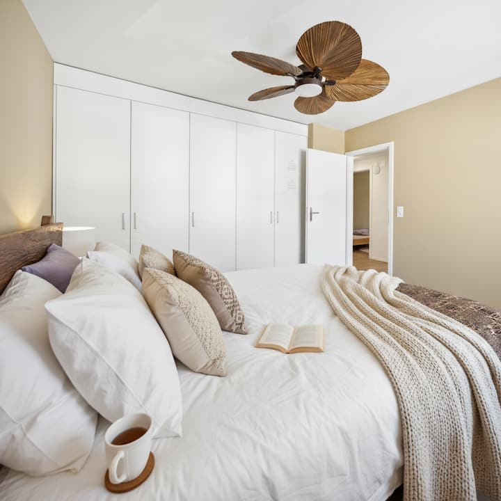 Chumba cha kulala cha 1 kina muundo wa kisasa na wenye nafasi kubwa na kitanda cha ukubwa wa king, feni ya dari na kabati kubwa la nguo lililojengwa, na kuunda mapumziko ya starehe na maridadi.