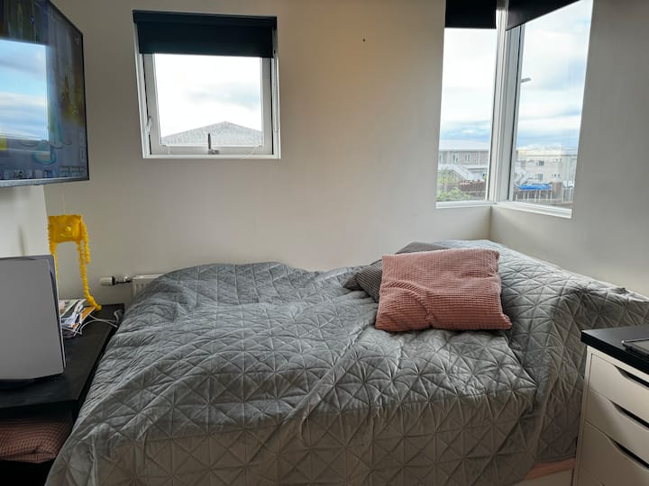 Spavaća soba na srednjem katu s bračnim krevetom, televizorom, ormarom i malim radnim stolom. 